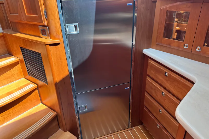Slide: The Image of Interior of 2022 Sabre 48 Salon Express with stainless steel fridge and wooden cabinetry. - 43