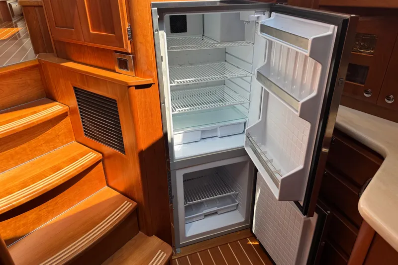 Slide: The Image of Open refrigerator inside 2022 Sabre 48 Salon Express yacht, showcasing wooden interior and stairs. - 44