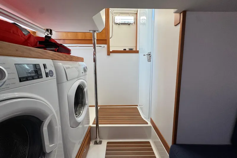 Slide: The Image of Laundry area inside 2022 Sabre 48 Salon Express yacht, featuring washer and dryer. - 62
