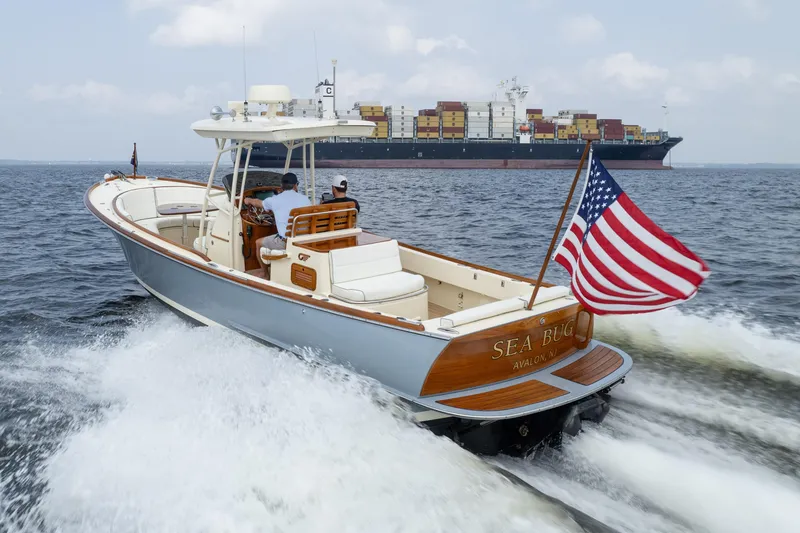 Slide: The Image of 2017 Hinckley Talaria 29C cruising with American flag, container ship in background. - 13