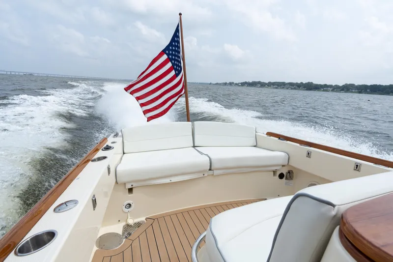 Slide: The Image of 2017 Hinckley Talaria 29C cruising with American flag, featuring elegant deck and seating. - 16