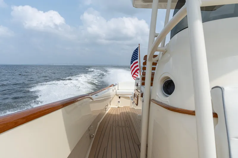 Slide: The Image of Hinckley Talaria 29C 2017 cruising on open water, American flag waving, wooden deck visible. - 27