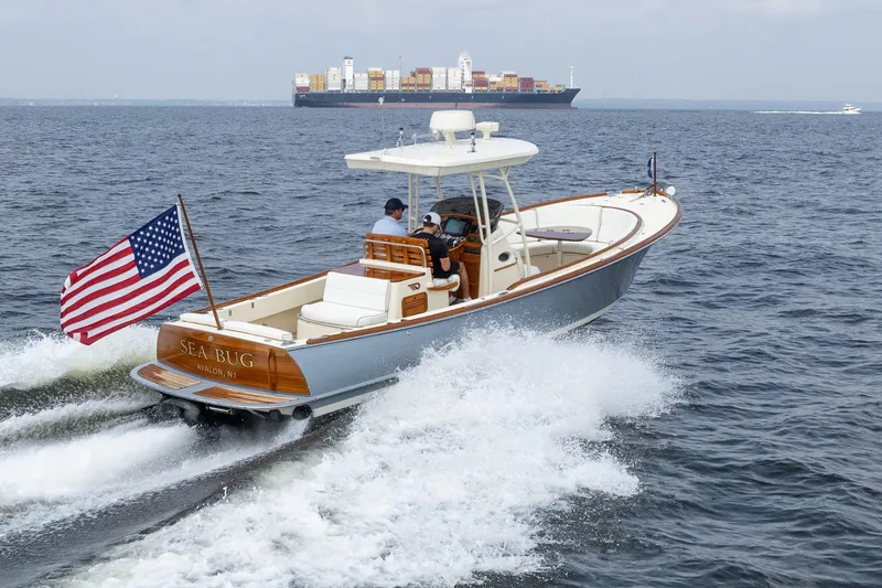 Slide: The Image of 2017 Hinckley Talaria 29C boat cruising with American flag, container ship in background. - 9