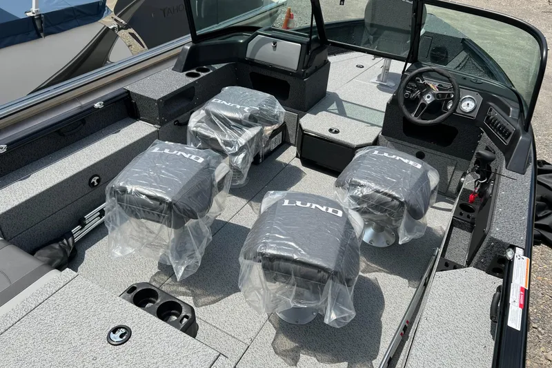 Slide: The Image of 2026 Lund 1875 Impact XS Sport boat interior with four covered seats and steering console. - 17