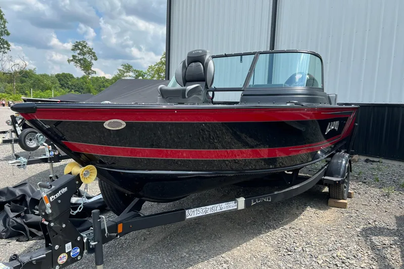 Slide: The Image of 2026 Lund 1875 Impact XS Sport boat with red and black design on a trailer. - 19