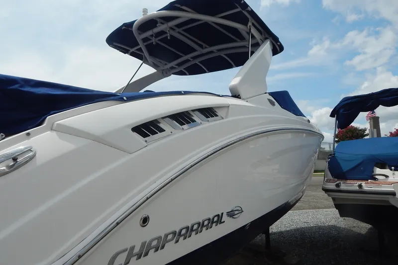 Slide: The Image of 2016 Chaparral 277 SSX boat with blue canopy, docked under a cloudy sky. - 10