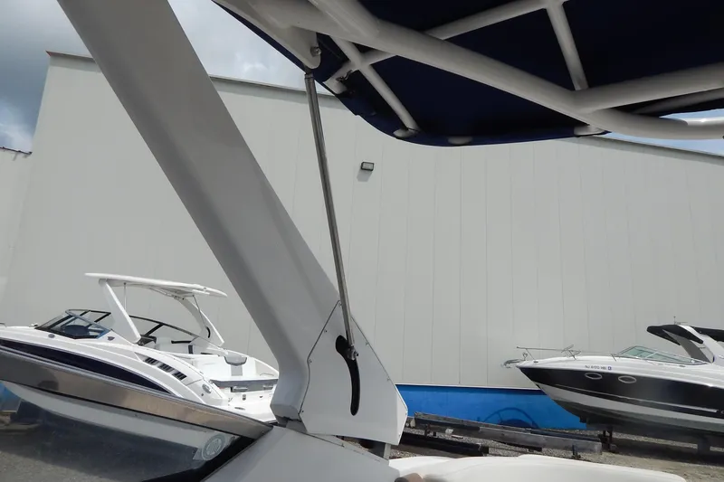 Slide: The Image of 2016 Chaparral 277 SSX boat with canopy, docked near other boats, against a warehouse backdrop. - 44