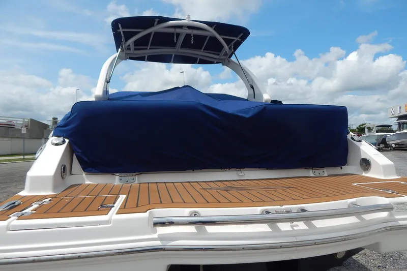 Slide: The Image of 2016 Chaparral 277 SSX boat with blue cover and wooden deck, under a clear sky. - 7
