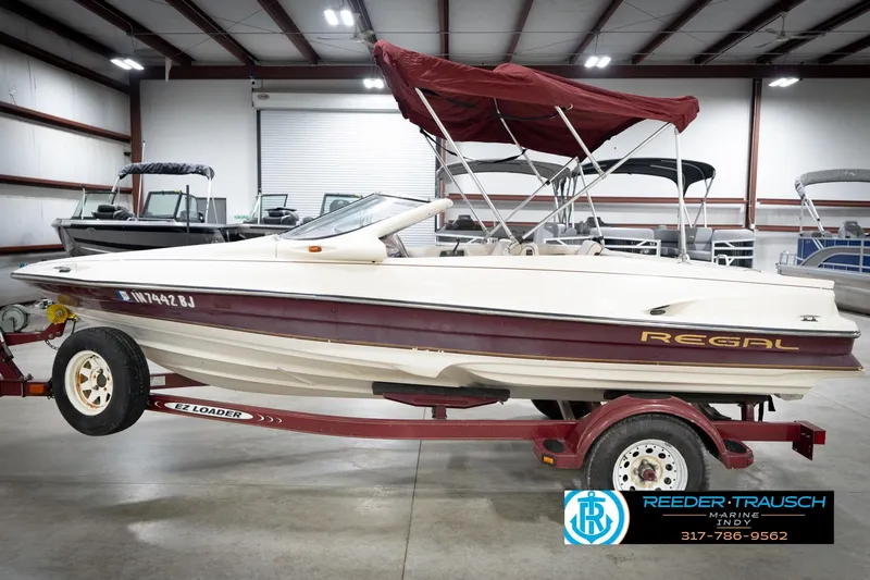 Slide: The Image of 1998 Regal 1700 LSR boat on trailer in indoor showroom, featuring maroon and white design. - 10