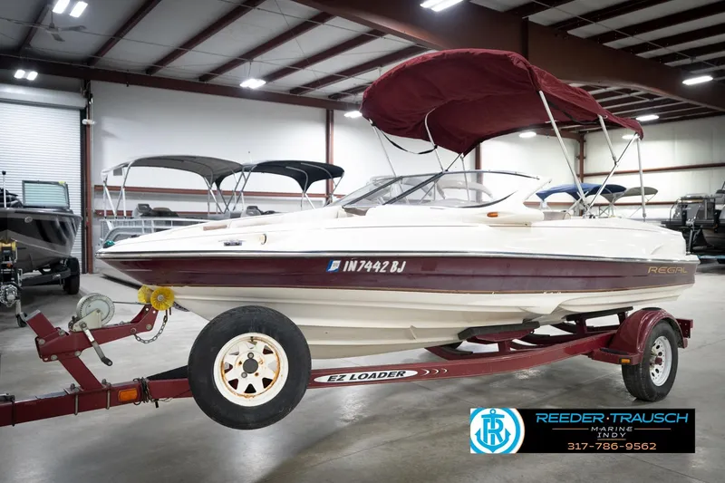 Slide: The Image of 1998 Regal 1700 LSR boat on trailer in indoor showroom, featuring maroon and white design. - 3