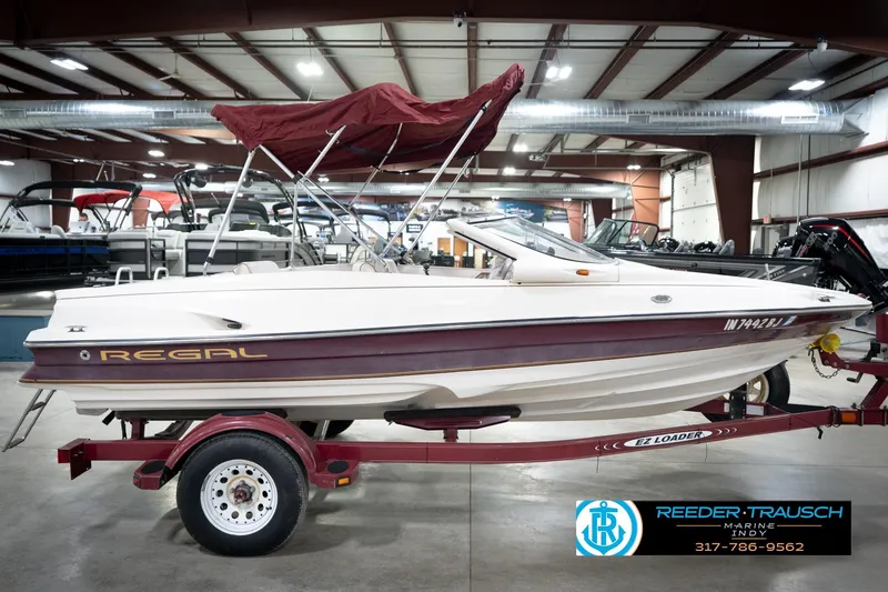 Slide: The Image of 1998 Regal 1700 LSR boat with maroon accents on a trailer in a showroom. - 6
