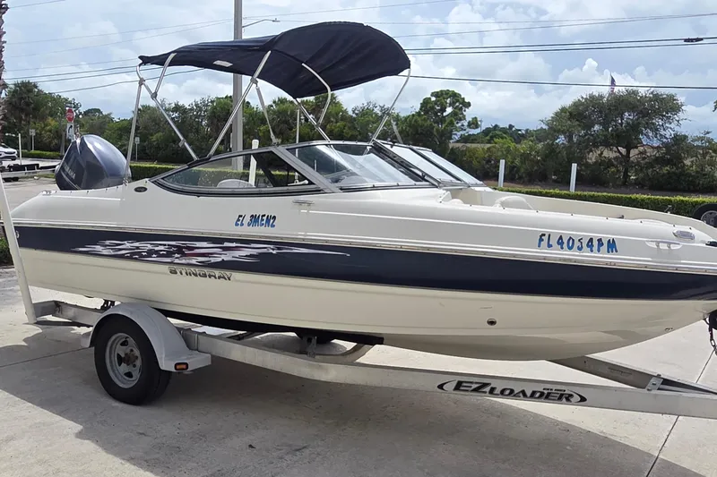 Slide: The Image of 2013 Stingray 194 LX boat on trailer with canopy, parked outdoors. - 3