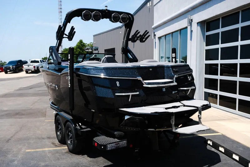 Slide: The Image of 2023 MasterCraft XStar boat on trailer, parked outside a building. - 2