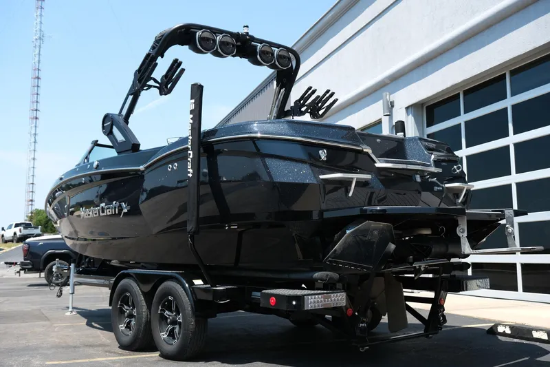 Slide: The Image of 2023 MasterCraft XStar boat on trailer, sleek black design, parked near a building. - 32