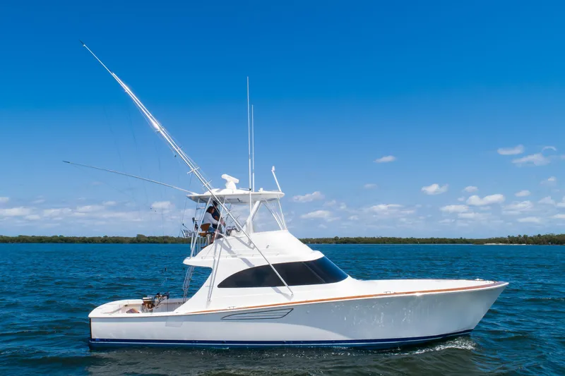 Slide: The Image of 2023 Viking 46 Billfish yacht cruising on open water under clear blue sky. - 0