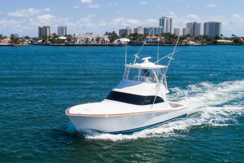 Slide: The Image of 2023 Viking 46 Billfish yacht cruising on blue water near city skyline. - 2