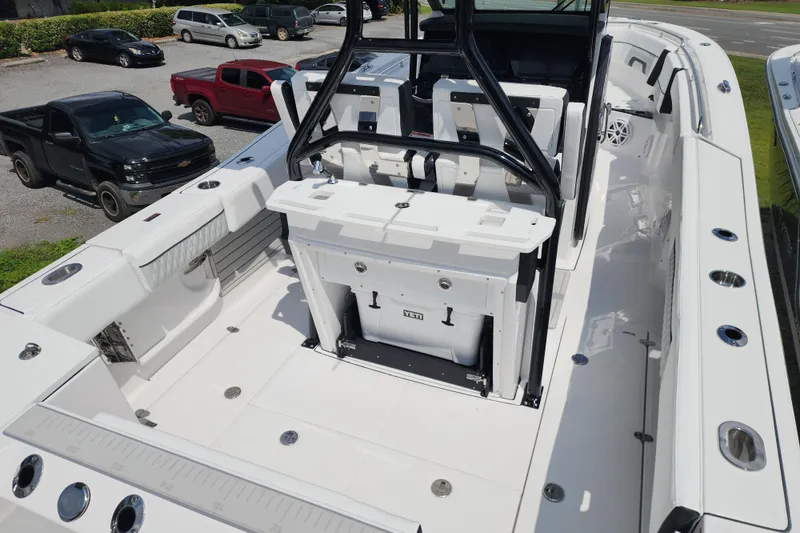 Slide: The Image of 2026 Blackfin 272 CC boat interior with seating and storage, parked near vehicles. - 6