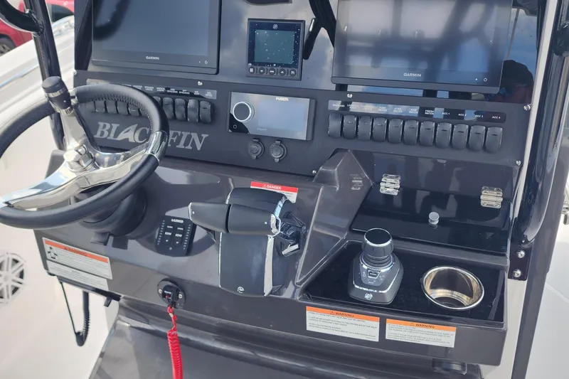 Slide: The Image of 2026 Blackfin 272 CC boat dashboard with steering wheel, controls, and Garmin displays. - 9