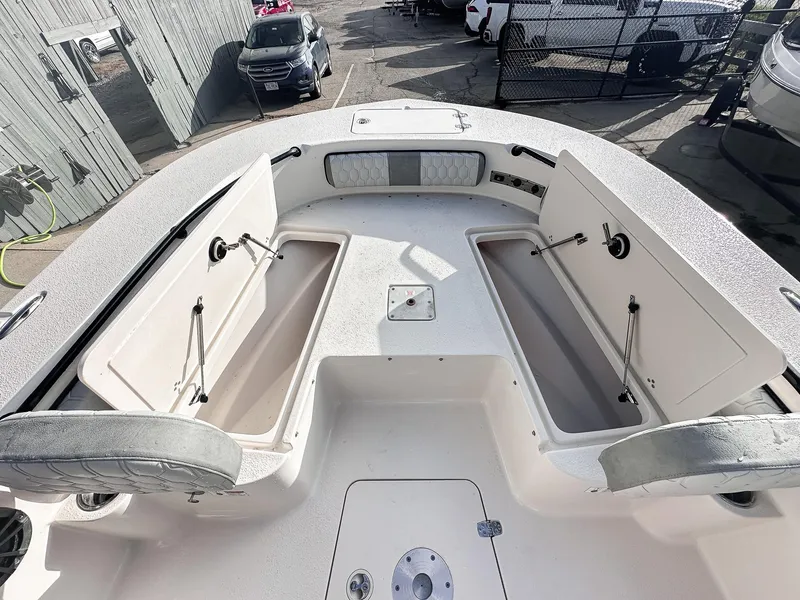 Slide: The Image of 2026 Carolina Skiff 22 Ultra Elite boat with T-top and seating, parked near a house. - 33