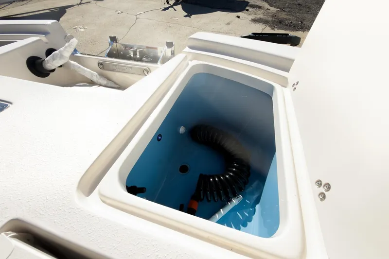 Slide: The Image of 2026 Carolina Skiff 22 Ultra Elite boat storage compartment with hose inside. - 44