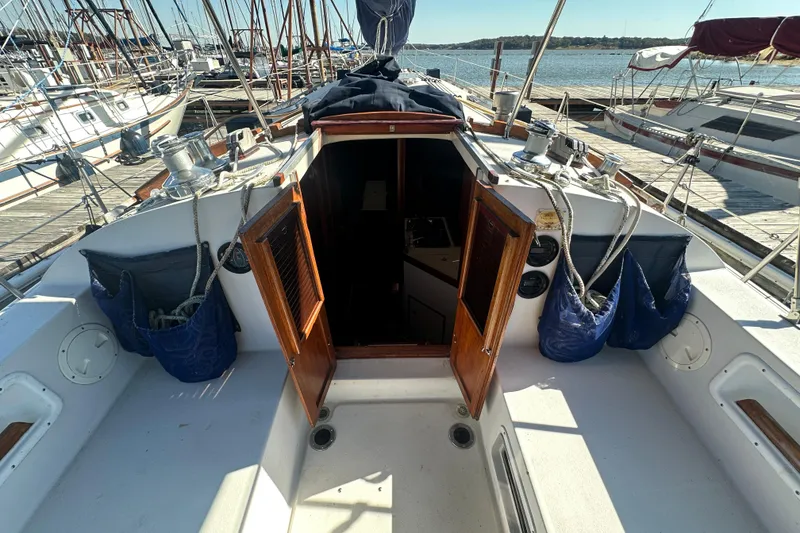 Slide: The Image of 1989 Nonsuch 36 sailboat cockpit with open cabin doors, docked at marina. - 11