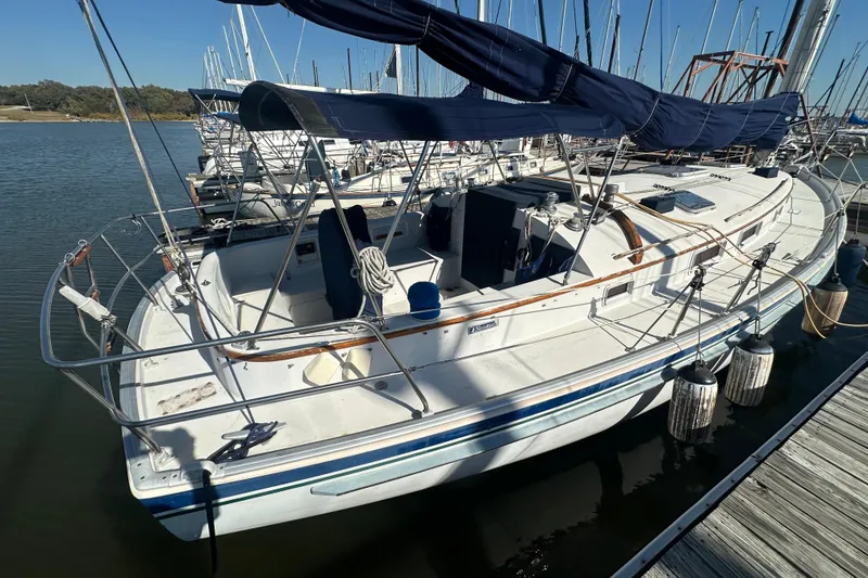 Slide: The Image of 1989 Nonsuch 36 sailboat docked at marina, featuring spacious cockpit and blue canopy. - 2