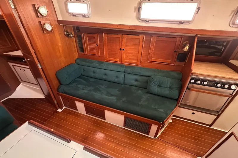 Slide: The Image of Interior of 1989 Nonsuch 36 sailboat with green cushioned seating and wooden cabinetry. - 21