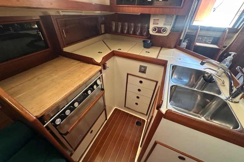 Slide: The Image of 1989 Nonsuch 36 yacht kitchen with stove, sink, and wooden cabinetry. - 25
