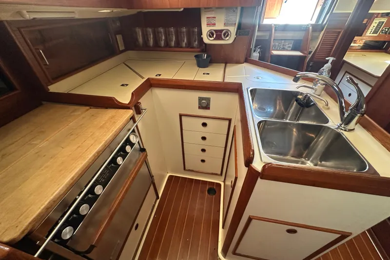 Slide: The Image of 1989 Nonsuch 36 yacht kitchen with dual sinks, stove, and wooden cabinetry. - 26