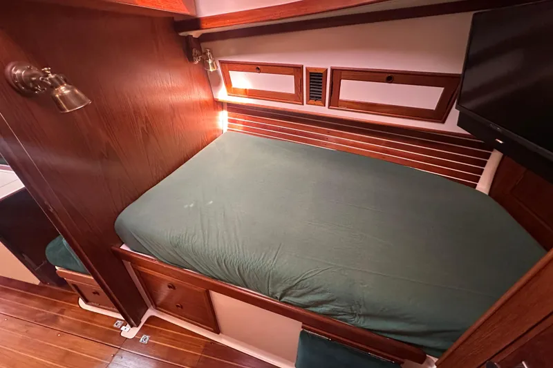 Slide: The Image of Cozy cabin interior of 1989 Nonsuch 36 sailboat with wooden accents and green bedding. - 31