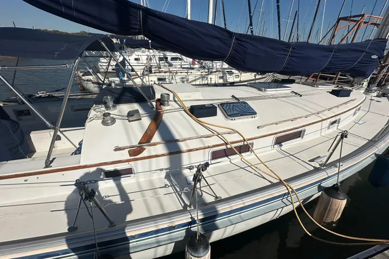 Slide: The Image of 1989 Nonsuch 36 sailboat docked, featuring a spacious deck and blue sail cover. - 4