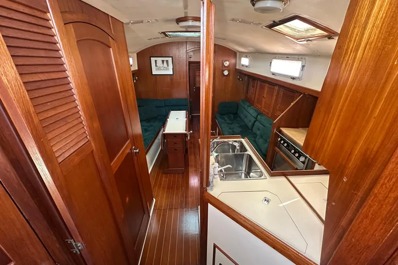 Slide: The Image of 1989 Nonsuch 36 yacht interior with wood finish, green seating, and kitchen area. - 40