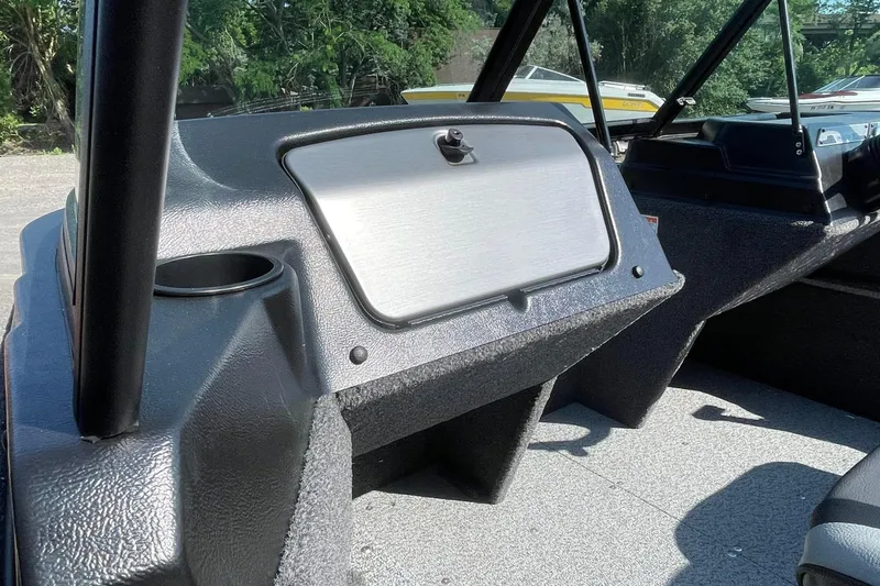 Slide: The Image of 2026 Lund 1650 Angler Sport boat interior with glove compartment and cup holder. - 16