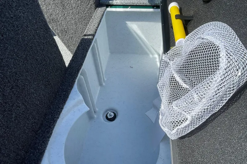 Slide: The Image of 2026 Lund 1650 Angler Sport boat interior with storage compartment and fishing net. - 6