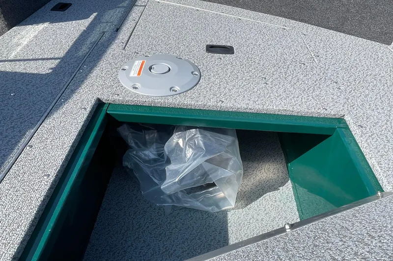 Slide: The Image of 2026 Lund 1650 Angler Sport boat storage compartment with open hatch and protective cover. - 9