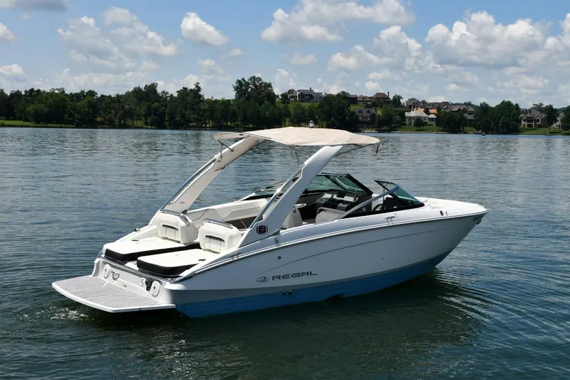 Slide: The Image of 2019 Regal LS4 boat on a serene lake with a clear sky backdrop. - 2