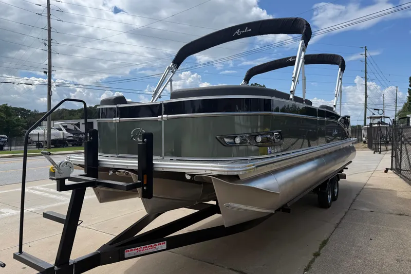 Slide: The Image of 2022 Avalon Catalina VRL 25' pontoon boat on trailer, parked outdoors under cloudy sky. - 3