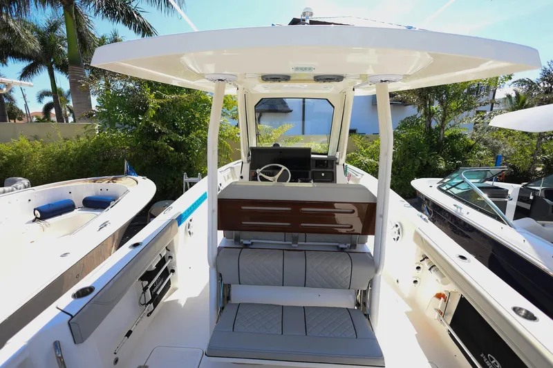 Slide: The Image of 2022 Pursuit S 288 Sport boat interior with seating and helm, surrounded by lush greenery. - 14
