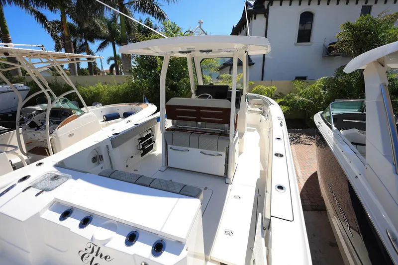 Slide: The Image of 2022 Pursuit S 288 Sport boat docked, featuring spacious deck and seating, surrounded by greenery. - 9