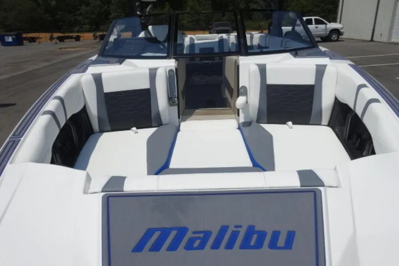 Slide: The Image of 2026 Malibu 23 MXZ boat interior with white and gray seating, parked outdoors. - 3