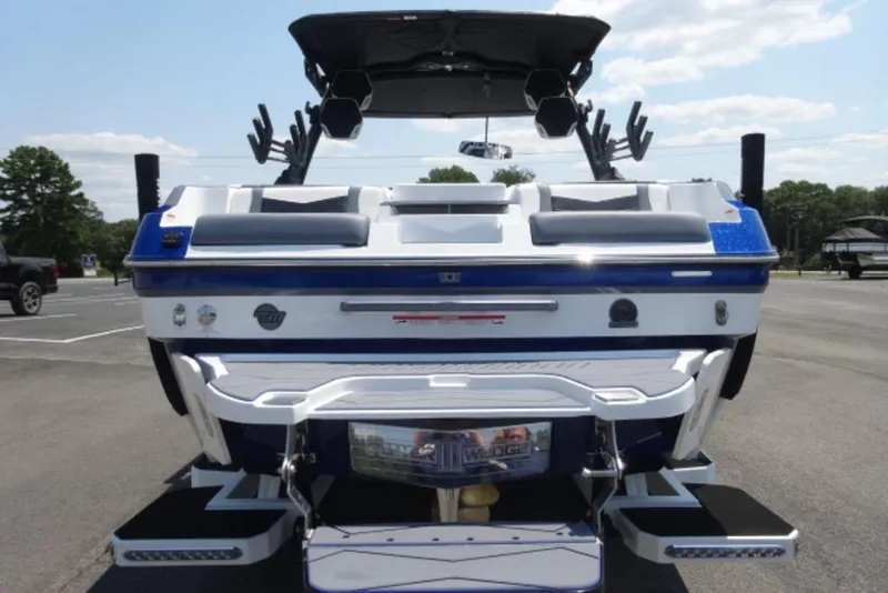 Slide: The Image of 2026 Malibu 23 MXZ boat, rear view, in a parking lot under a clear sky. - 4