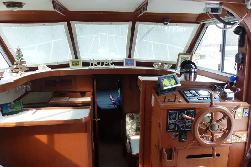Slide: The Image of 1987 Marine Trader Sundeck interior with wooden helm, navigation equipment, and cozy cabin decor. - 10