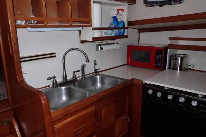 Slide: The Image of 1987 Marine Trader Sundeck kitchen with double sink, red microwave, and stove. - 12