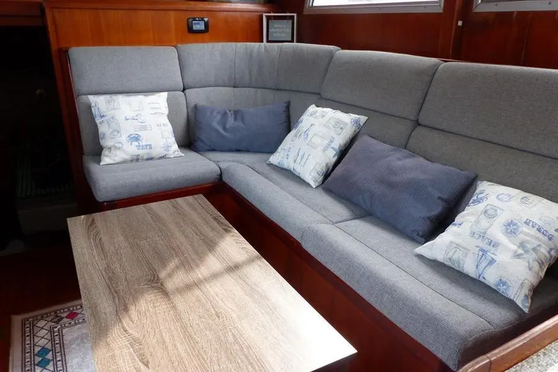 Slide: The Image of 1987 Marine Trader Sundeck interior with gray seating, decorative pillows, and wooden table. - 19