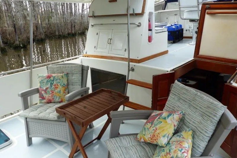 Slide: The Image of 1987 Marine Trader Sundeck with cozy seating and floral cushions on a serene waterway. - 23
