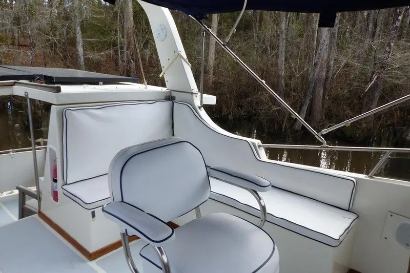 Slide: The Image of 1987 Marine Trader Sundeck boat interior with cushioned seating and wooded backdrop. - 25