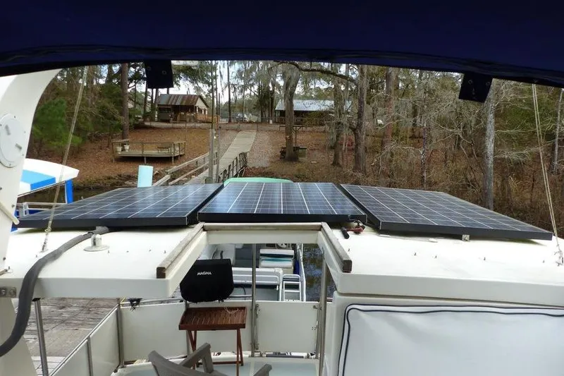 Slide: The Image of 1987 Marine Trader Sundeck with solar panels, docked near a wooded area. - 27
