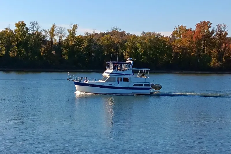 Slide: The Image of 1987 Marine Trader Sundeck cruising on a calm river with autumn trees in the background. - 3