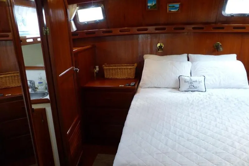 Slide: The Image of Cozy bedroom interior of 1987 Marine Trader Sundeck yacht with wood paneling and white bedding. - 35