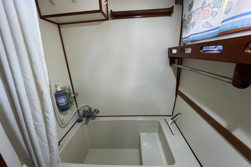 Slide: The Image of Compact bathroom with tub in 1987 Marine Trader Sundeck boat, featuring wooden accents and storage. - 36